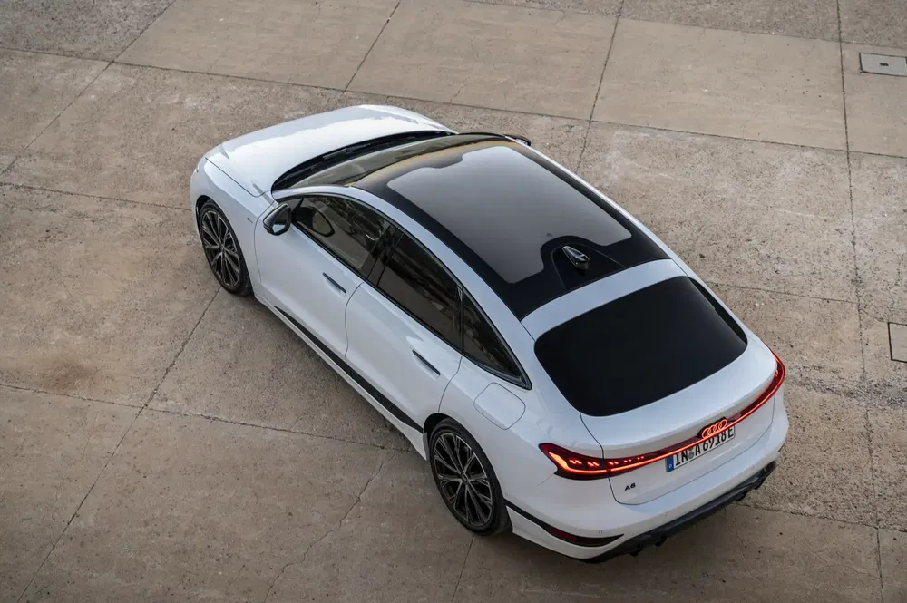 Vue aérienne d'une Audi A6 blanche avec un toit panoramique sur une surface en béton.