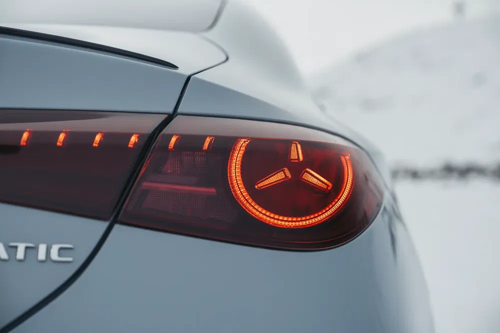 Achterlicht van Mercedes 4MATIC brandend, stijlvol winterdesign op besneeuwde achtergrond.
