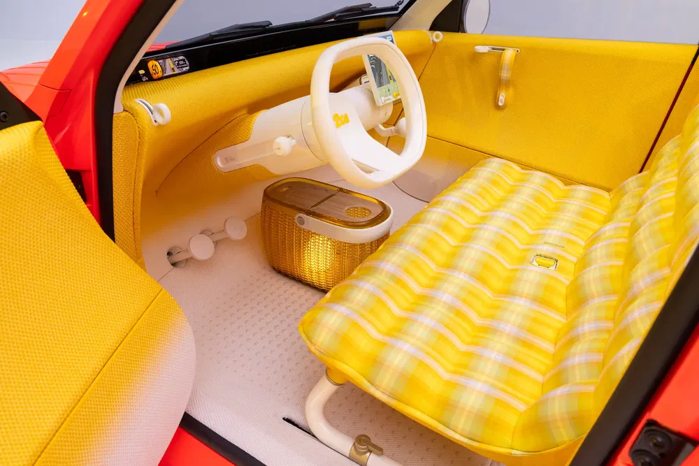 Intérieur rétro de la Renault 5, avec sièges jaunes et volant blanc moderne.