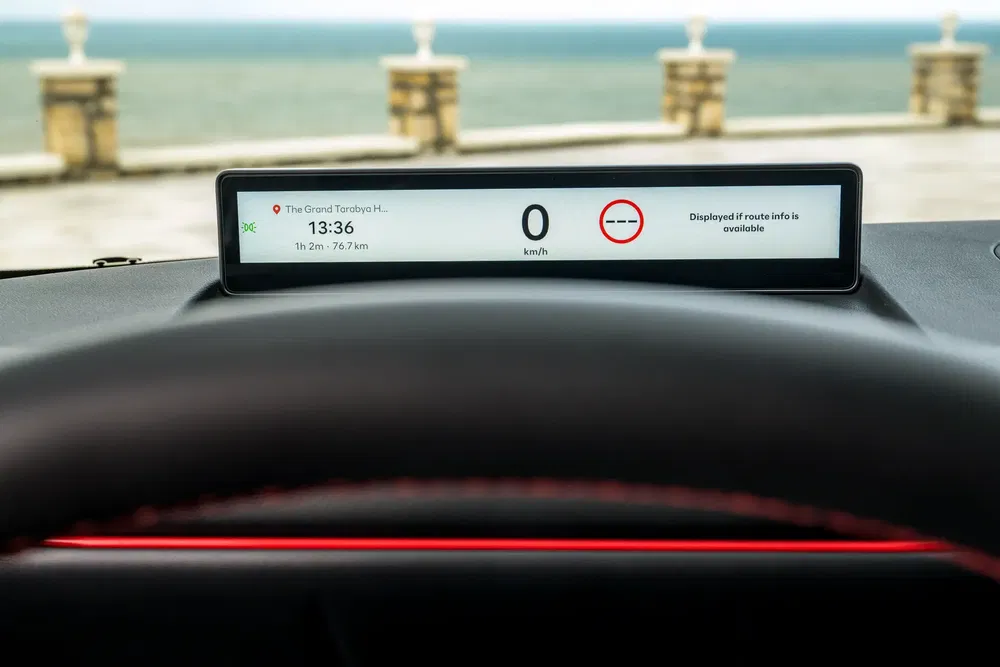 Digitale auto dashboard met navigatie en snelheidsmeter, uitzicht op zee.