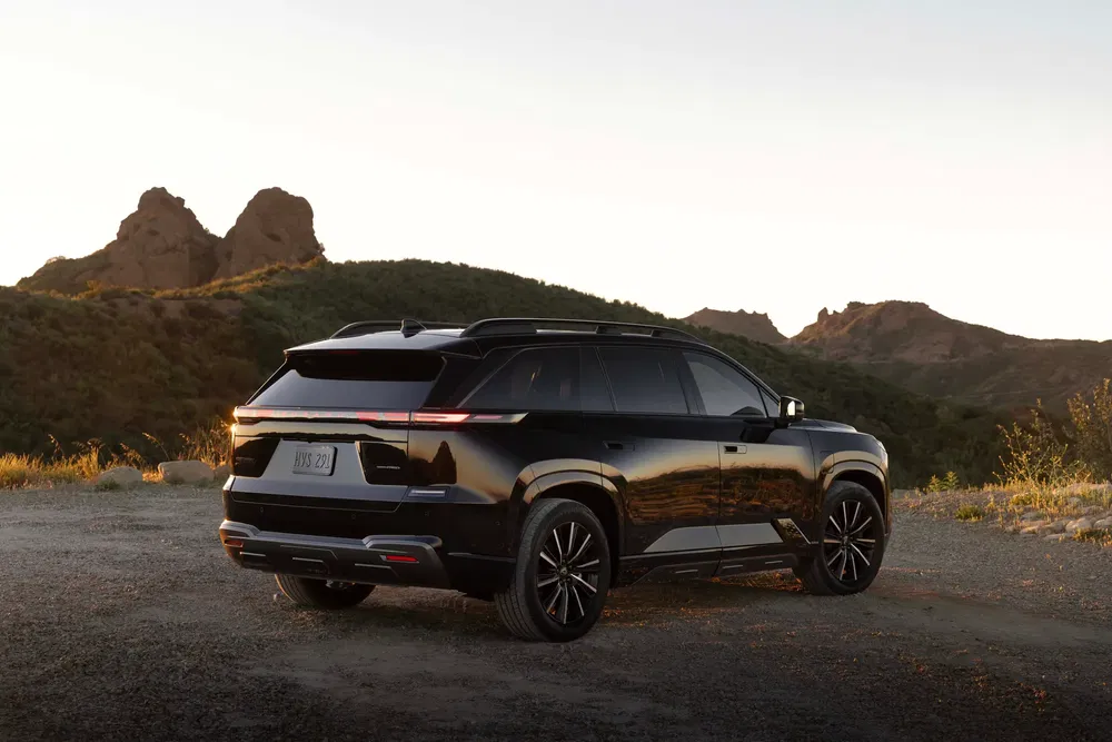 SUV noir Fisker en plein air devant un paysage montagneux au coucher du soleil.
