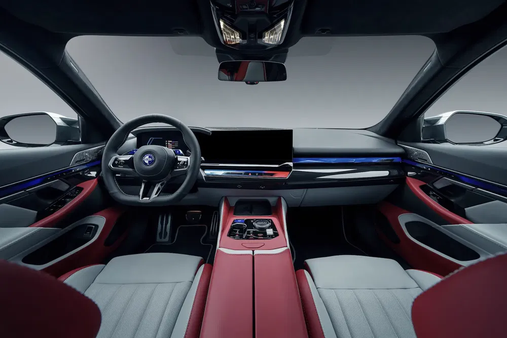 Intérieur moderne de voiture Maserati avec tableau de bord numérique et sièges en cuir rouge et gris.