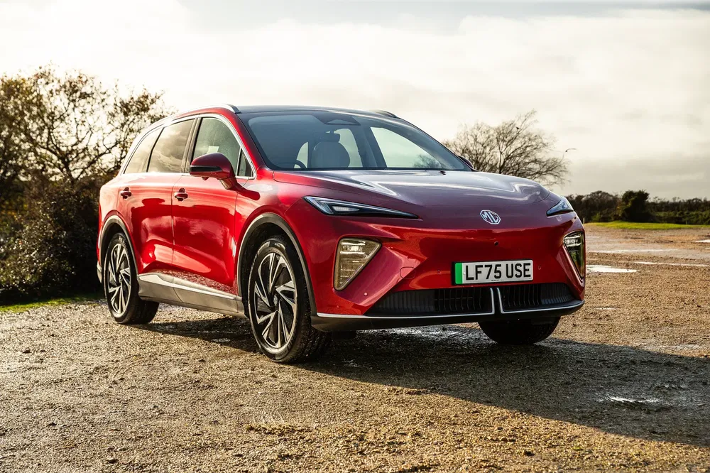Rode MG elektrische SUV op natte weg onder bewolkte hemel.