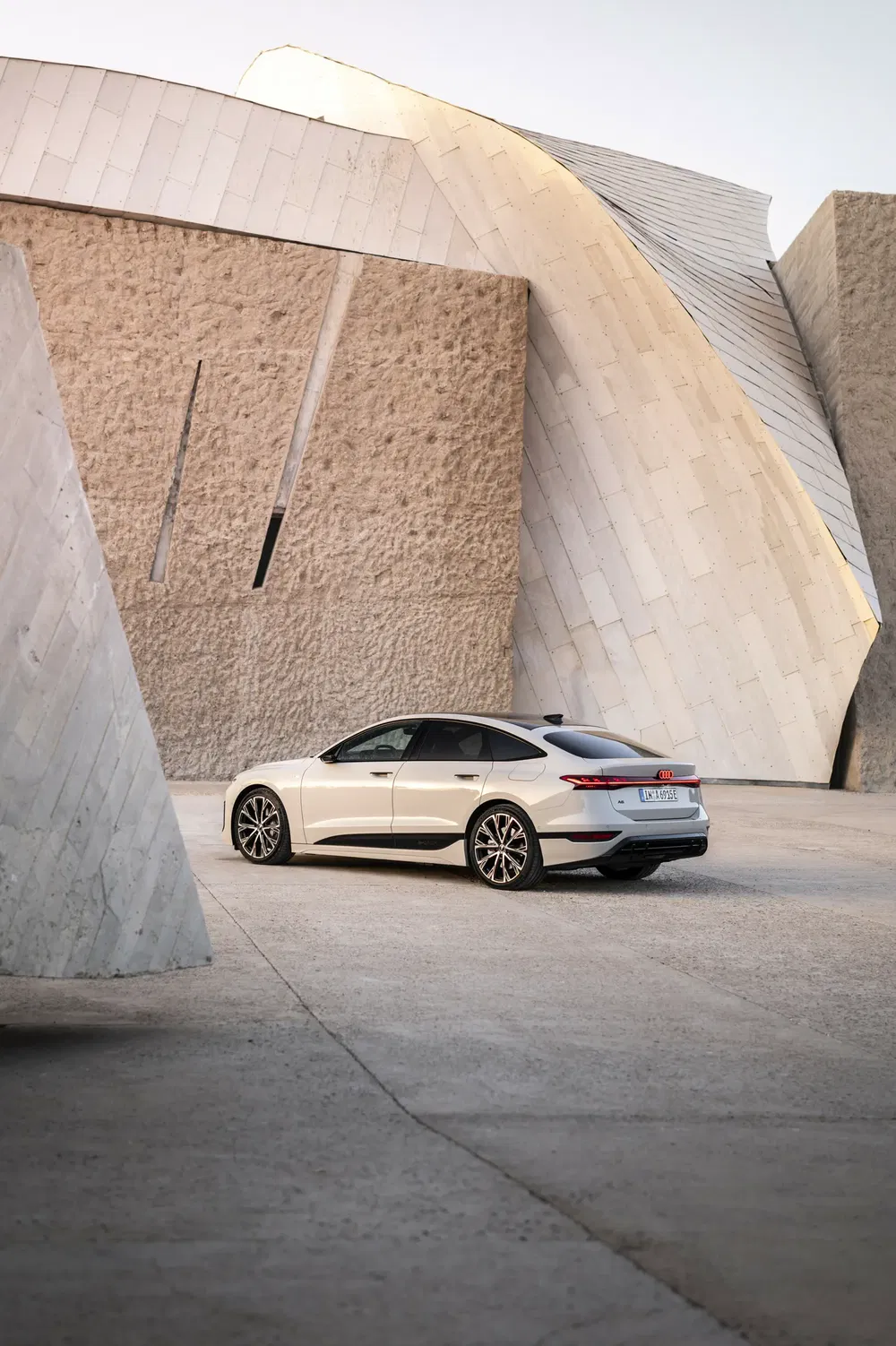 Audi e-tron GT blanche devant une architecture moderne en béton, design futuriste.