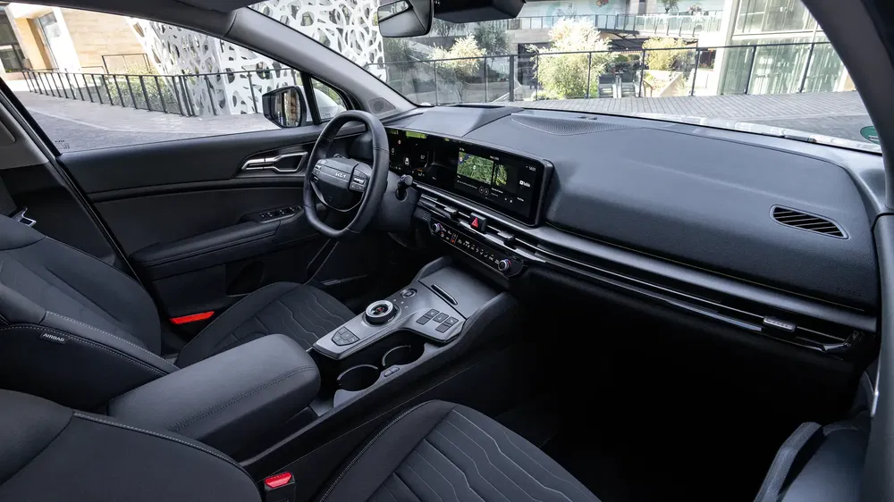 Intérieur moderne de la Kia Sportage, avec tableau de bord numérique et sièges avant élégants.