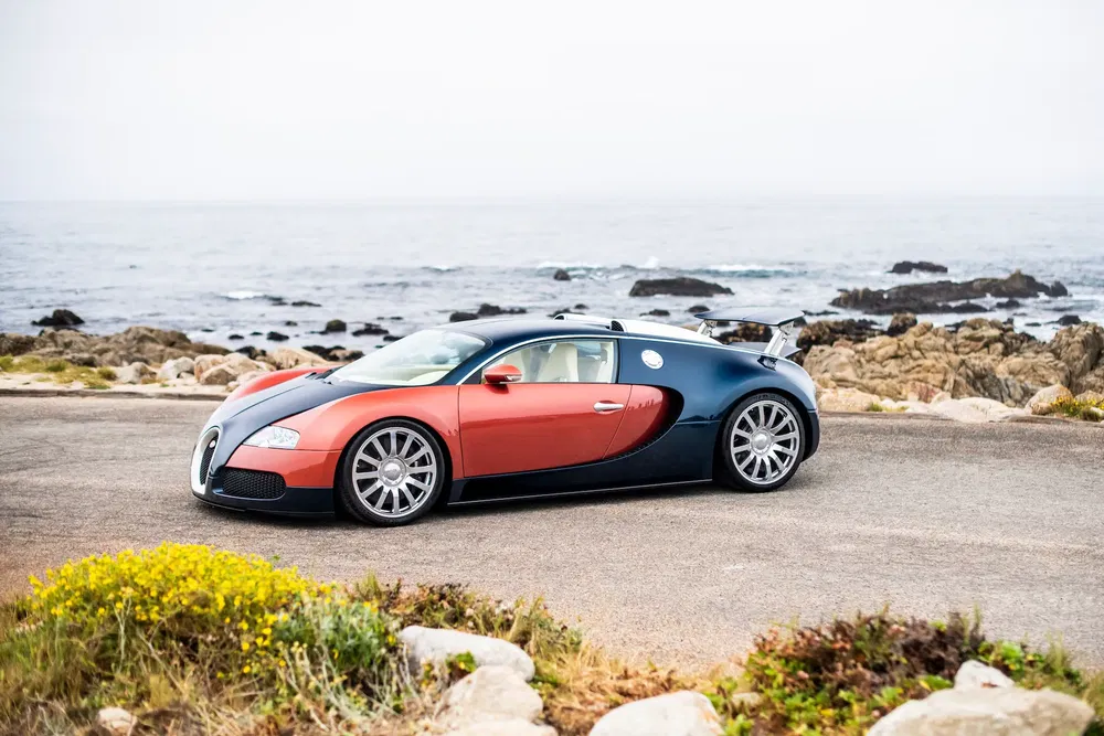 Bugatti Veyron rouge et noir garée près de la côte rocheuse.