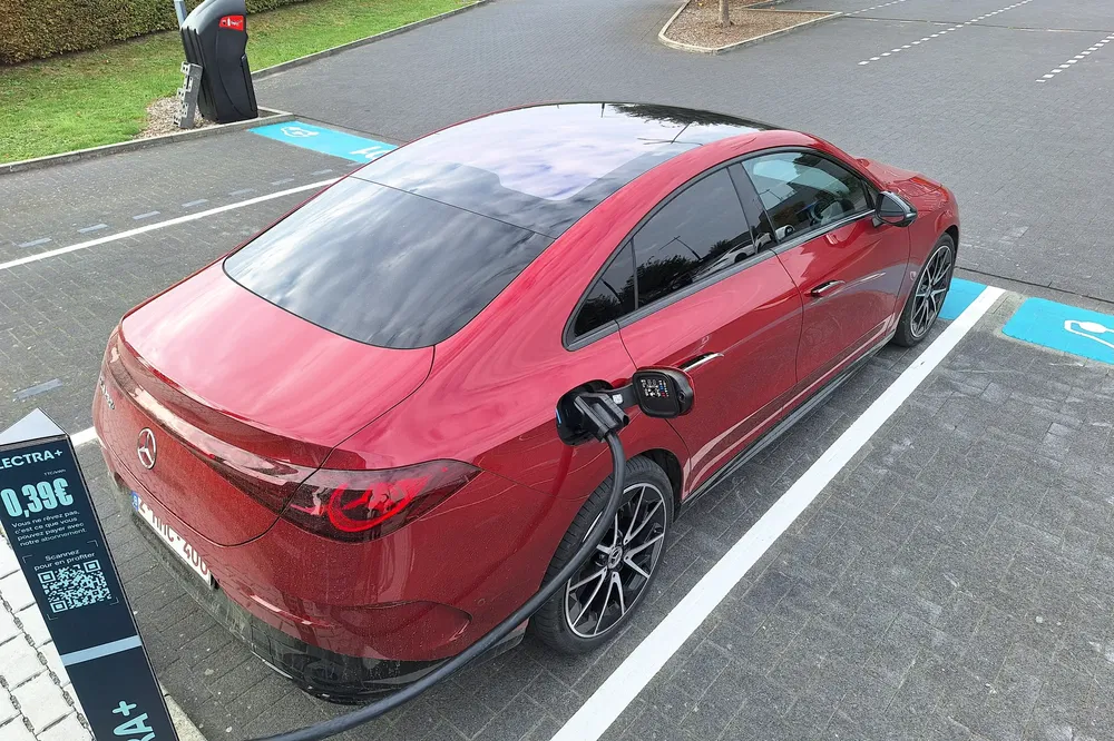 Rode elektrische Mercedes-Benz auto aan het opladen bij een modern laadstation.