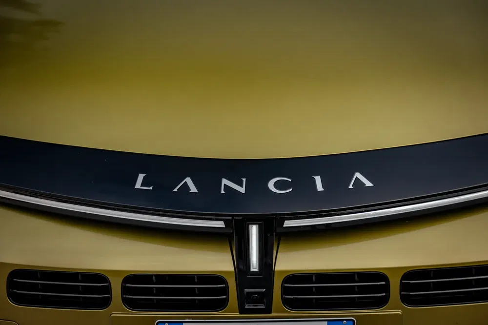 Capot de voiture Lancia jaune avec logo distinctif en gros plan.