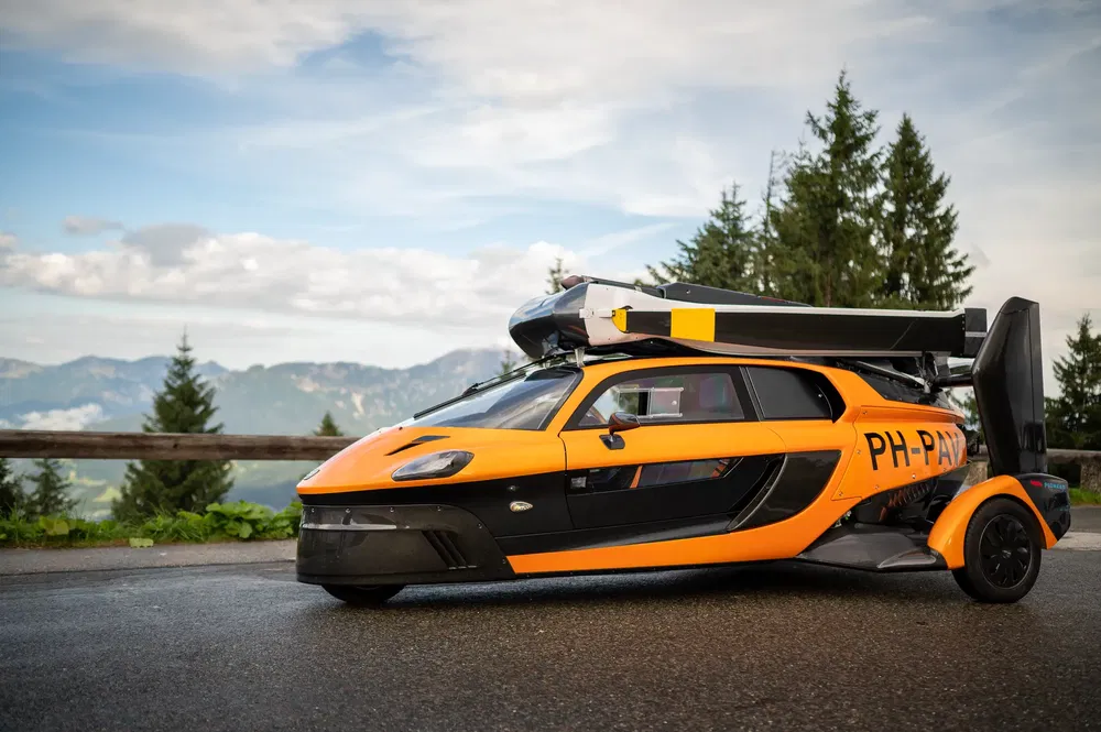 Voiture volante PAL-V Liberty orange en montagne, innovation automobile révolutionnaire.