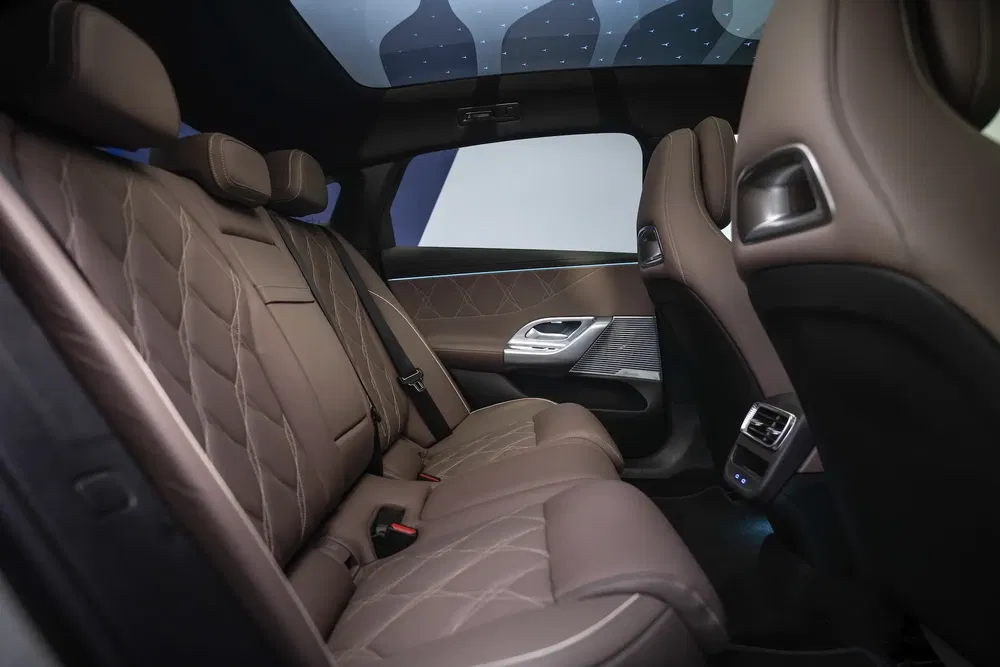 Intérieur luxe BMW avec sièges arrière en cuir, toit panoramique étoilé.