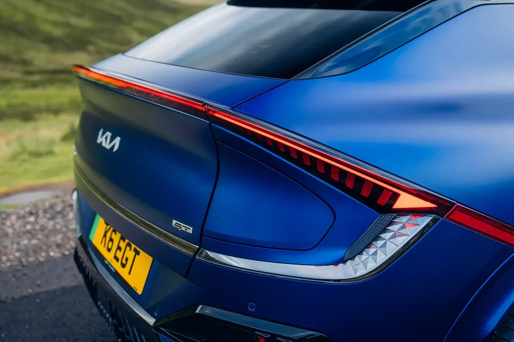 Vue arrière de la Kia EV6 bleu avec feux arrière élégants sur route panoramique.