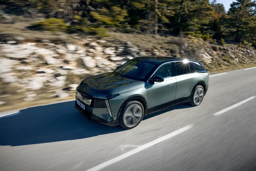 Moderne Citroën SUV rijdt op zonnige landelijke weg, met bosrijke achtergrond.
