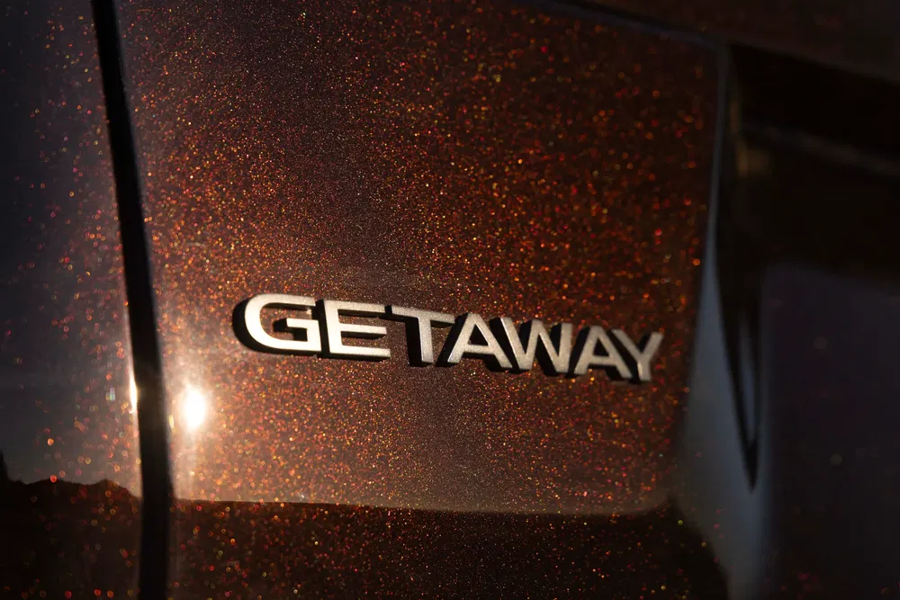 Inscription "GETAWAY" sur carrosserie pailletée d'un véhicule, exposition au soleil.