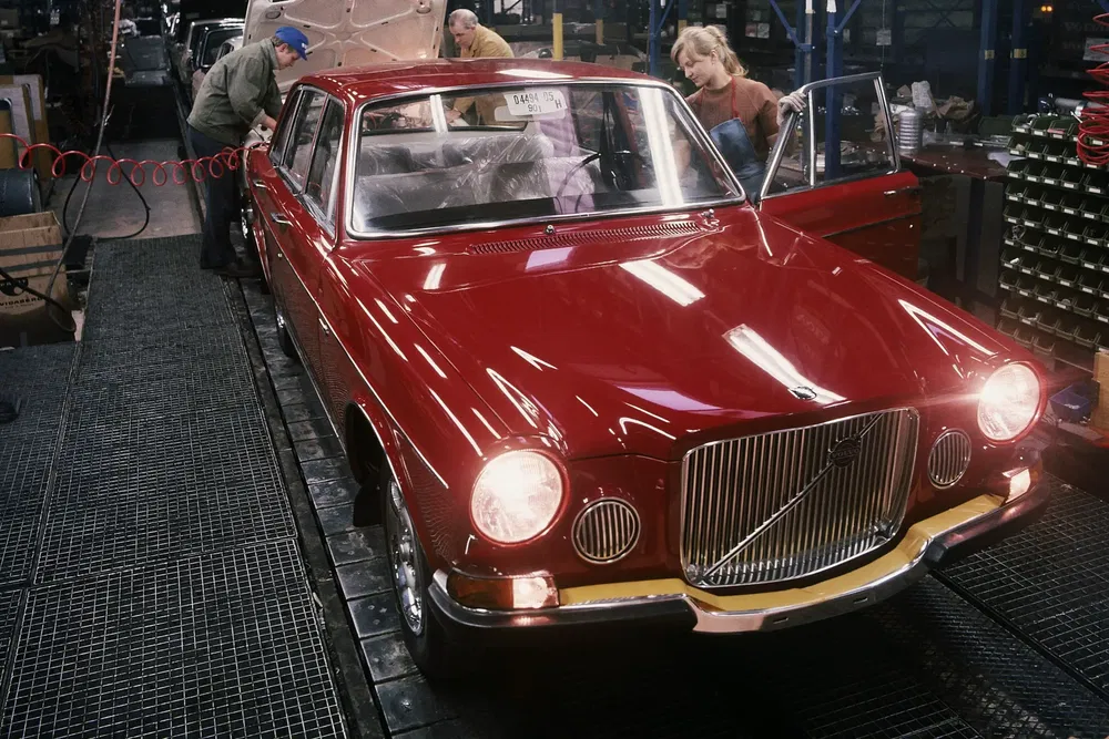Montage van een rode Volvo 164 op een autofabriek assemblagelijn.