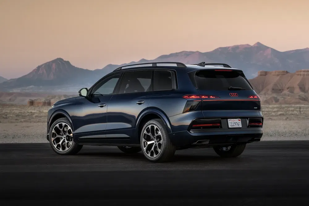 Donkerblauwe Audi Q6 e-tron SUV tegen schemerige bergachtergrond.