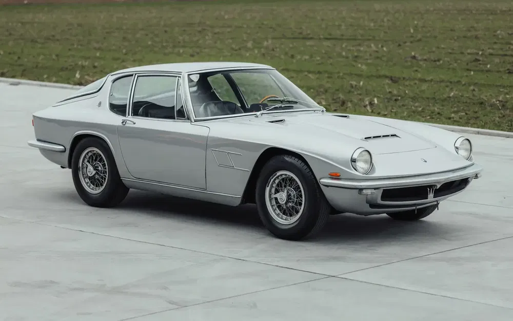 Maserati Mistral argentée classique stationnée sur fond de pelouse et béton.
