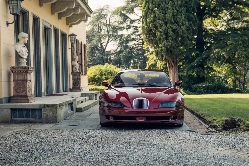 {"fr":"Voiture rouge classique garée devant une villa avec bustes en pierre et jardin paysager.","nl":"Klassieke rode auto geparkeerd voor villa met stenen bustes en landschapstuin."}