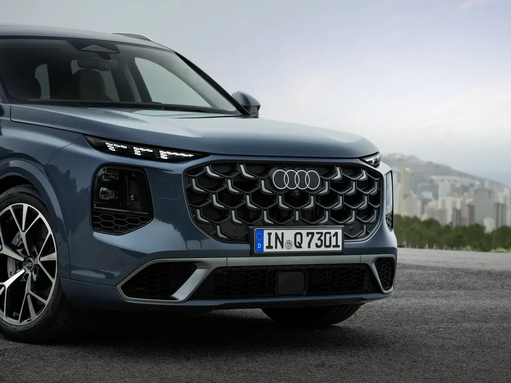 SUV Audi bleu avec calandre distinctive sur fond urbain flou.
