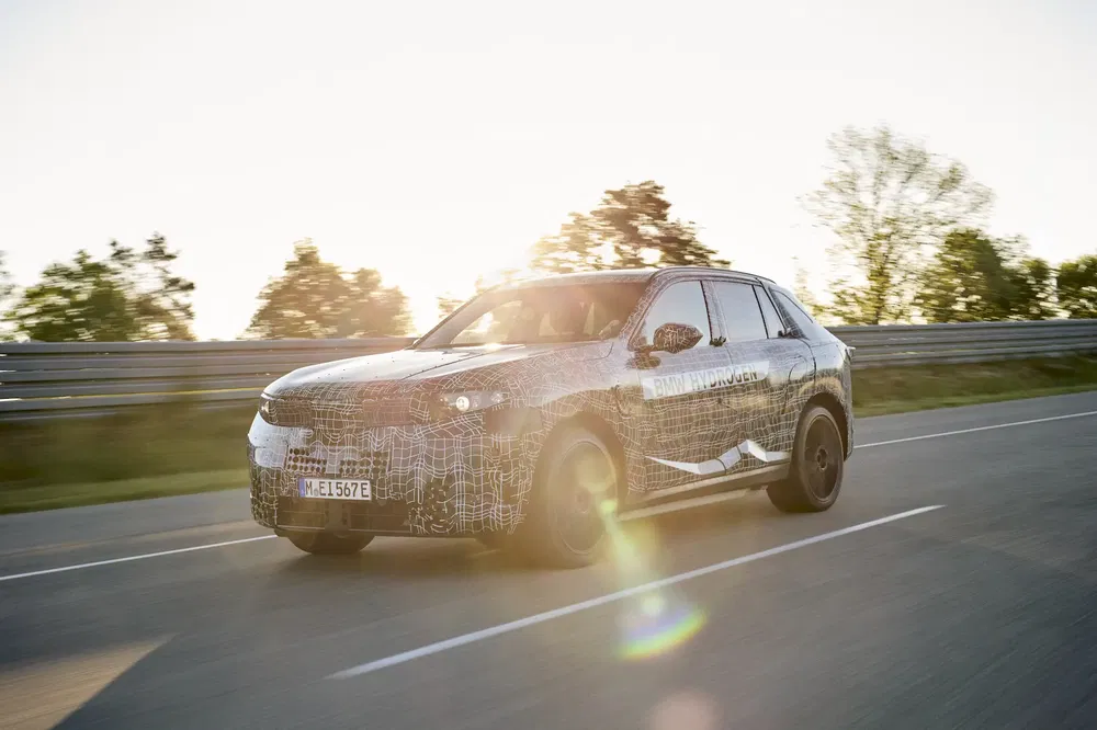 {"fr":"Prototype BMW iX SUV en test sur route ensoleillée.","nl":"BMW iX SUV prototype op zonnige weg in testrit."}