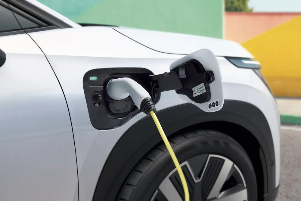 Recharge d'une voiture électrique Volvo avec câble, sur fond coloré.