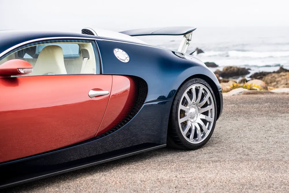 Voiture de luxe Bugatti Veyron en bord de mer avec jantes argentées brillantes.