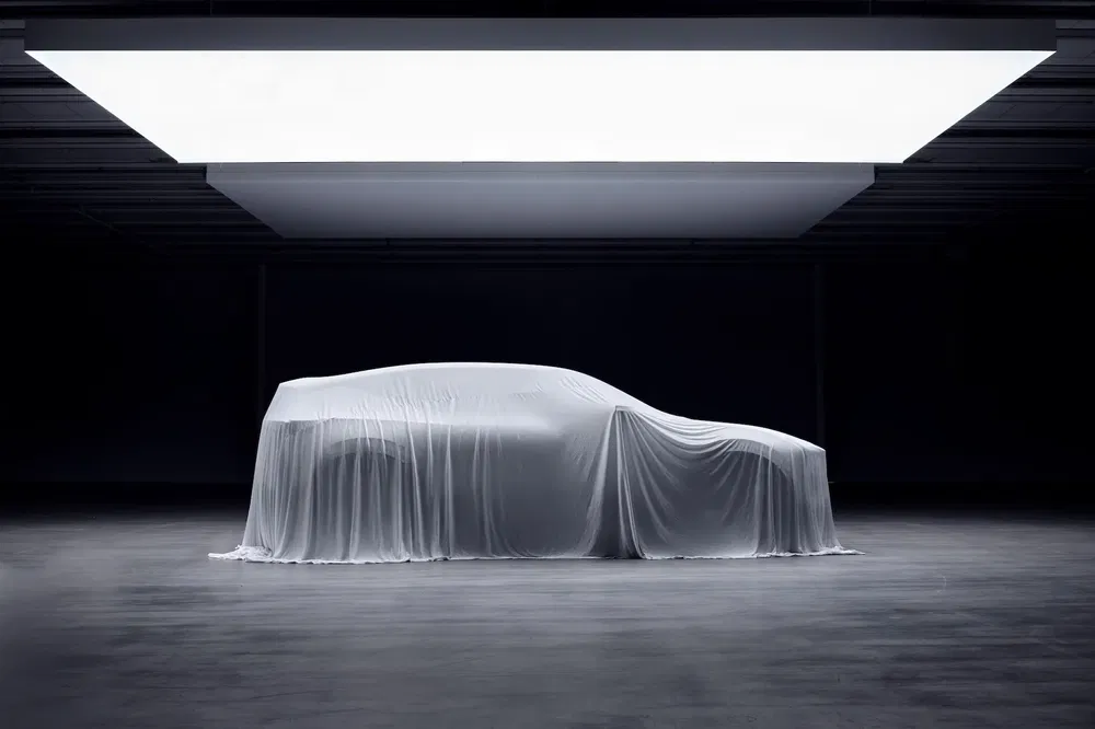 Auto onder hoes in moderne showroom met minimalistische verlichting, mysterieuze sfeer.