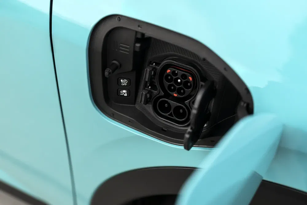 Laadpoort van een elektrische Hyundai Kona in turquoise, met zichtbare stekkers.