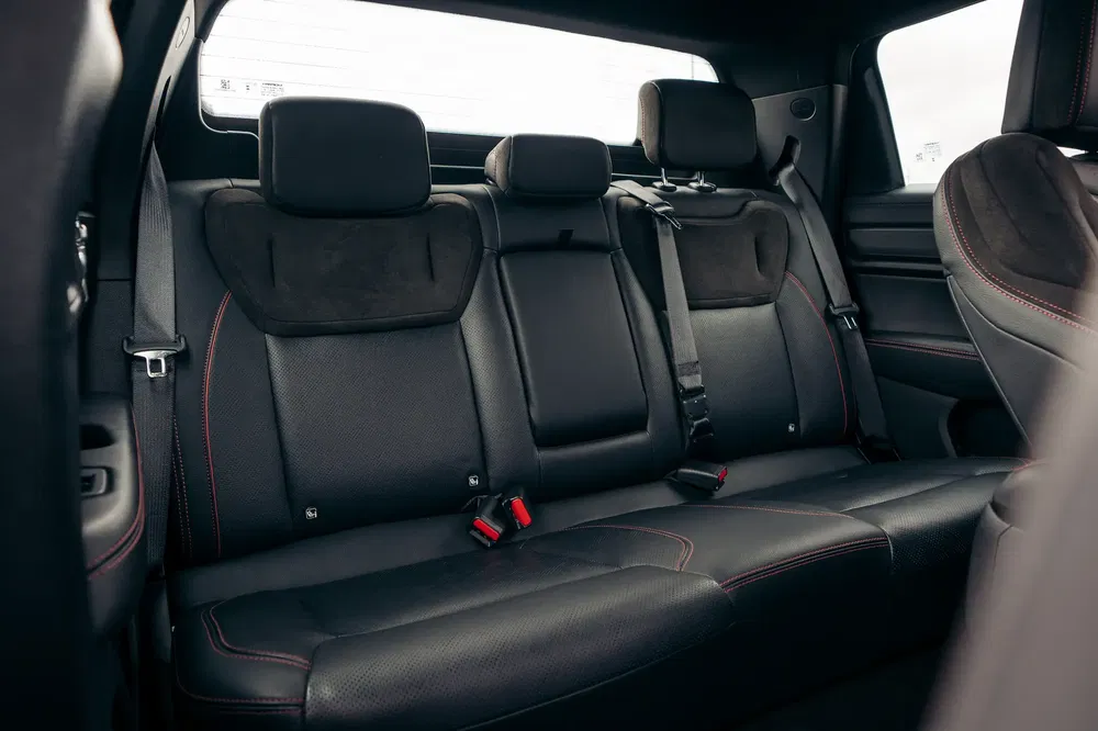 Achterbank van een moderne auto met zwarte leren stoelen en veiligheidsgordels.