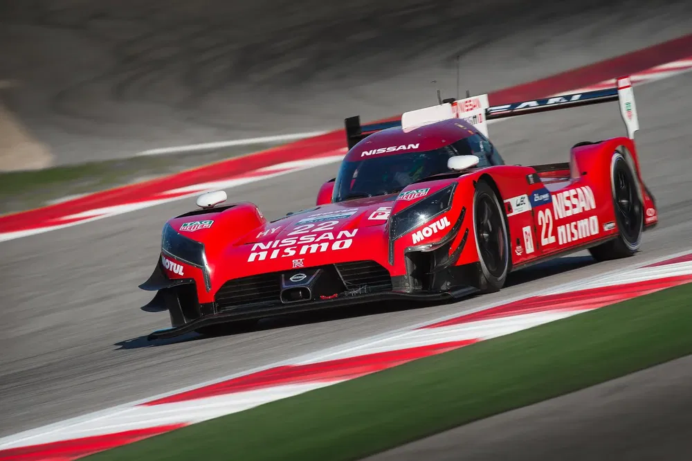 Voiture de course Nissan GT-R LM Nismo rouge sur circuit à grande vitesse.