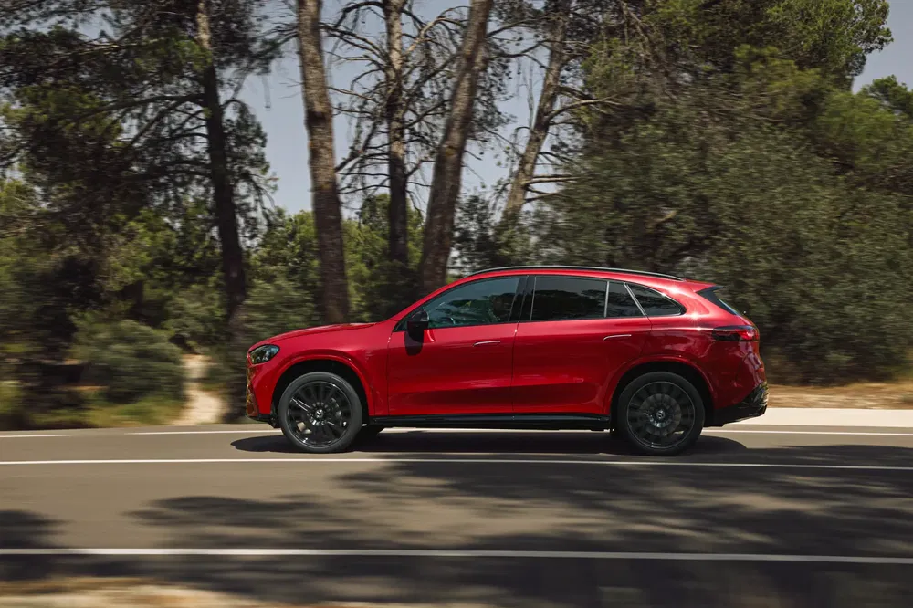 Mercedes-Benz GLC rouge roulant sur une route bordée d'arbres, en plein mouvement.