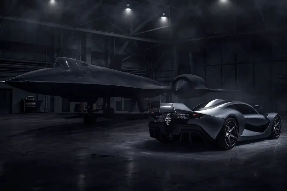 Supercar McLaren Speedtail argentée dans un hangar aéronautique avec un avion furtif noir.
