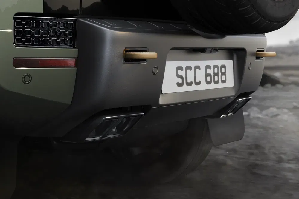 Vue arrière du Land Rover Defender avec pare-chocs robuste sur terrain accidenté.