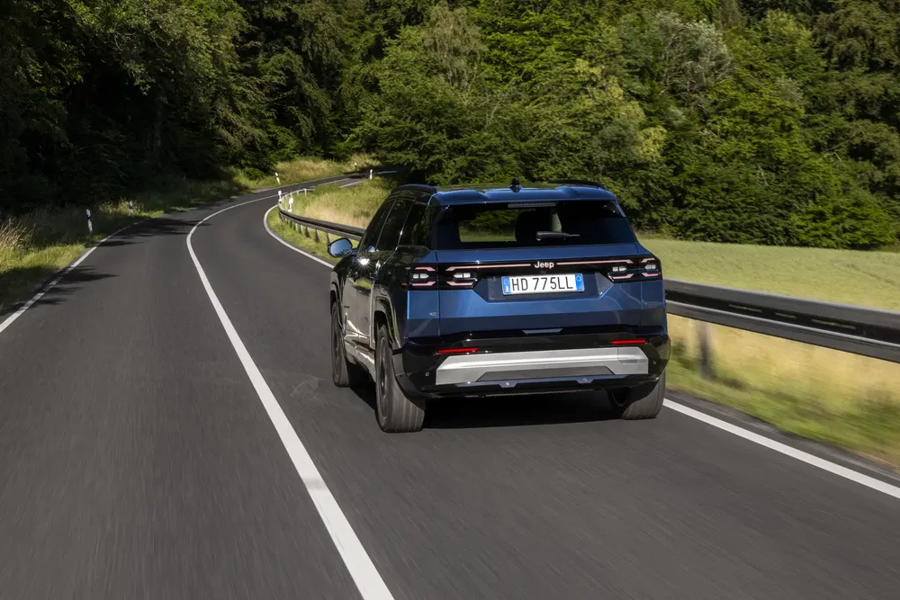 {"fr":"Jeep Grand Cherokee bleu conduisant sur une route sinueuse entourée de forêt dense.","nl":"Blauwe Jeep Grand Cherokee rijdt op bochtige weg omringd door dicht bos."}