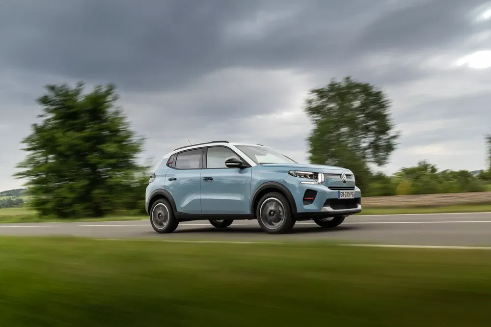 SUV compact bleu sur route de campagne sous un ciel nuageux.