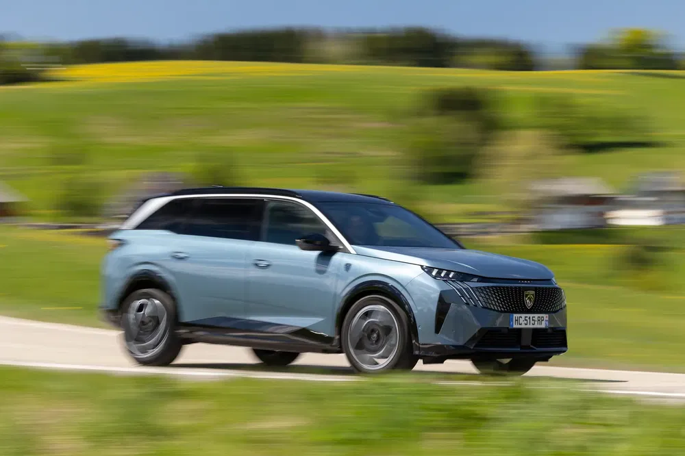 Peugeot 5008 2023 rijdt op een schilderachtige landelijke weg met veel groen.