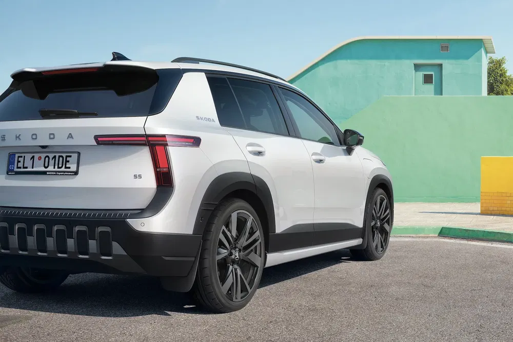 SUV Skoda blanc moderne garé devant un bâtiment coloré, design épuré et dynamique.