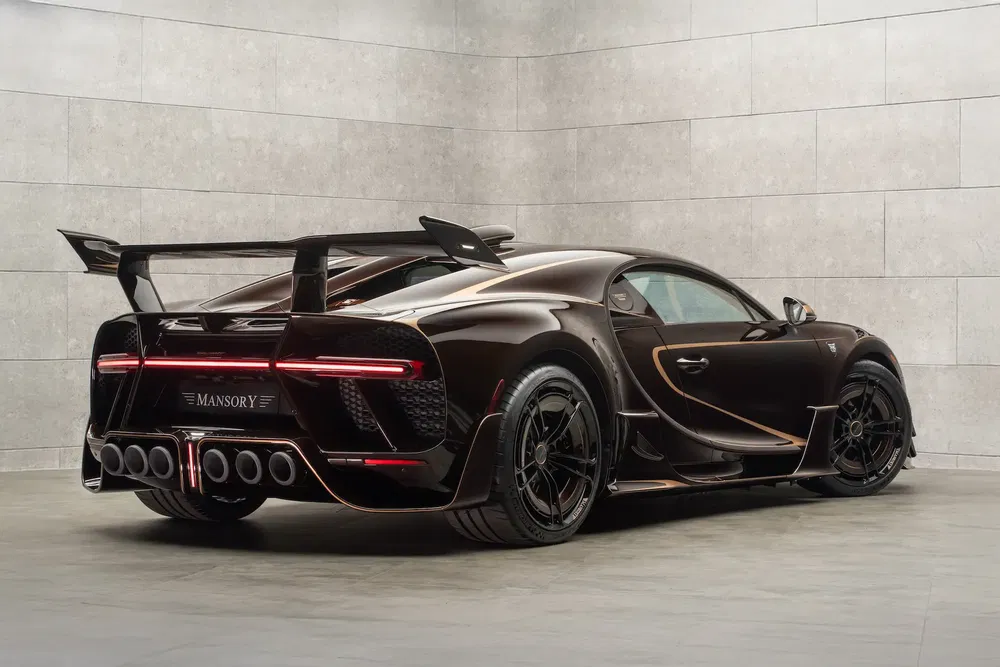 Bugatti Chiron Mansory Centuria marron avec aileron arrière imposant dans un garage moderne.