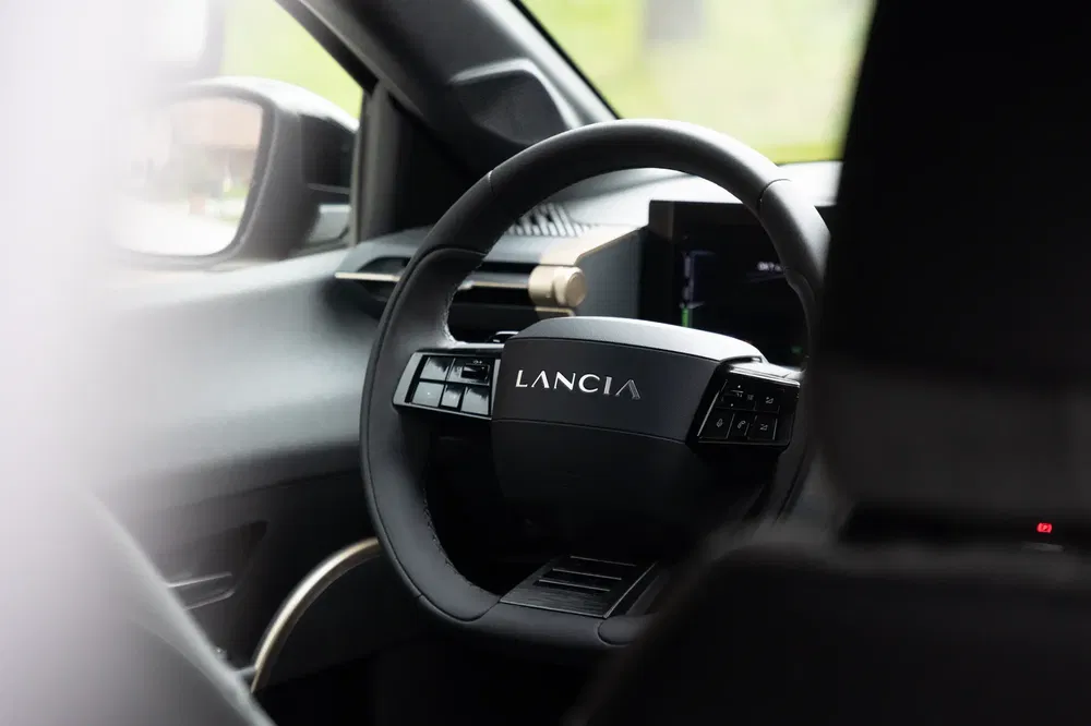 Volant de voiture Lancia moderne avec design minimaliste et écran de tableau de bord intégré.