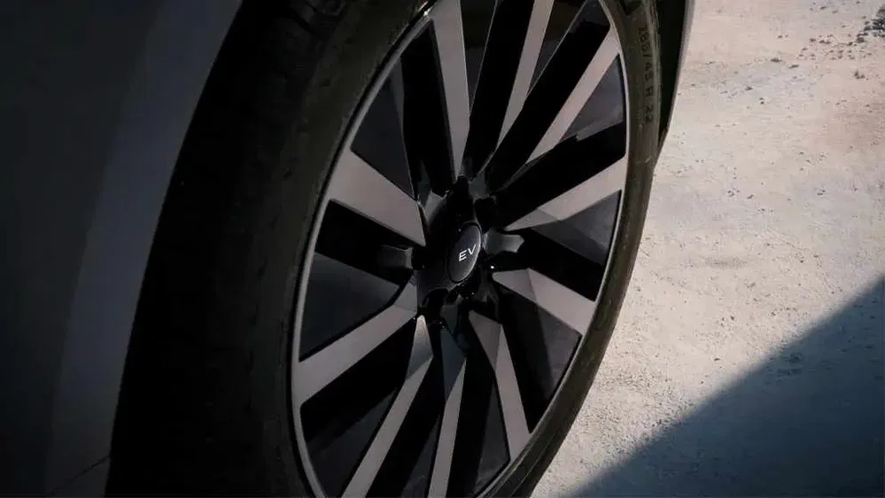 Gros plan d'une roue de voiture électrique avec jantes noires stylisées.