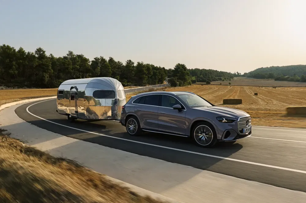 SUV Mercedes-Benz tractant une caravane moderne sur une route ensoleillée, paysage rural en arrière-plan.