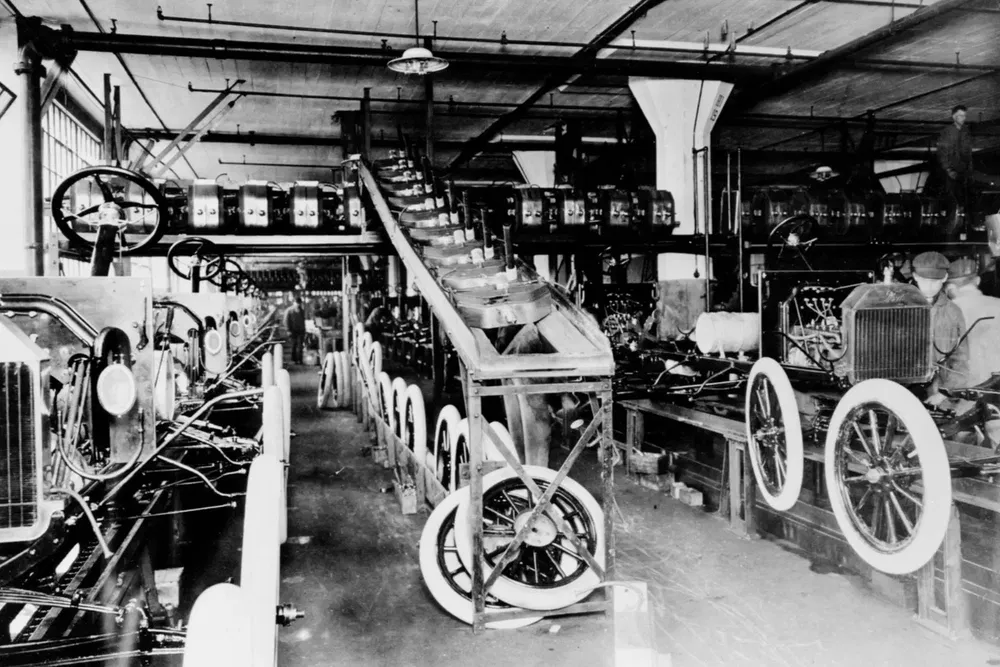 Chaîne de montage automobile Ford, châssis et roues alignés, début 20e siècle, production industrielle.
