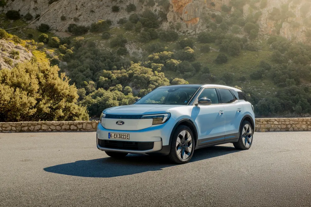Lichtblauwe elektrische Ford Explorer op een zonnige bergweg.
