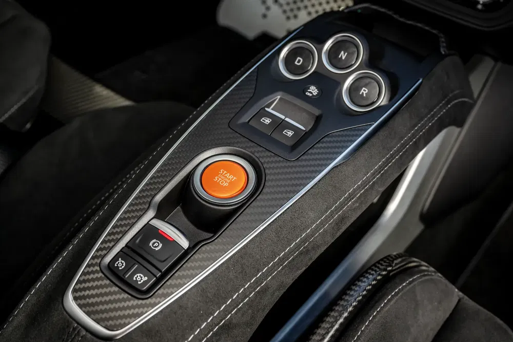 Middenconsole van McLaren met koolstofvezel afwerking en oranje start/stop knop.