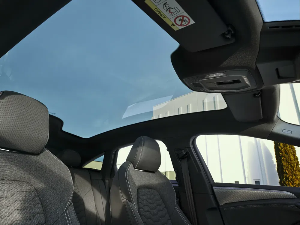 Intérieur de voiture moderne avec toit panoramique en verre, sièges avant élégants avec appuie-tête.