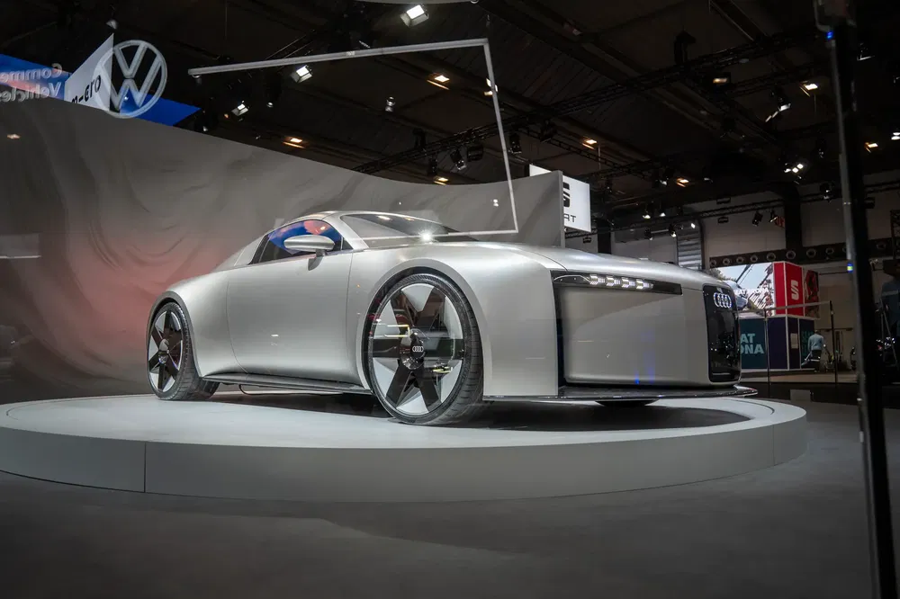 Audi électrique futuriste exposée lors d'un salon automobile moderne, éclairage dramatique.