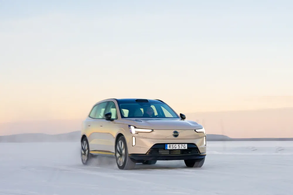 Volvo électrique haut de gamme roulant sur neige au coucher du soleil, carrosserie élégante.