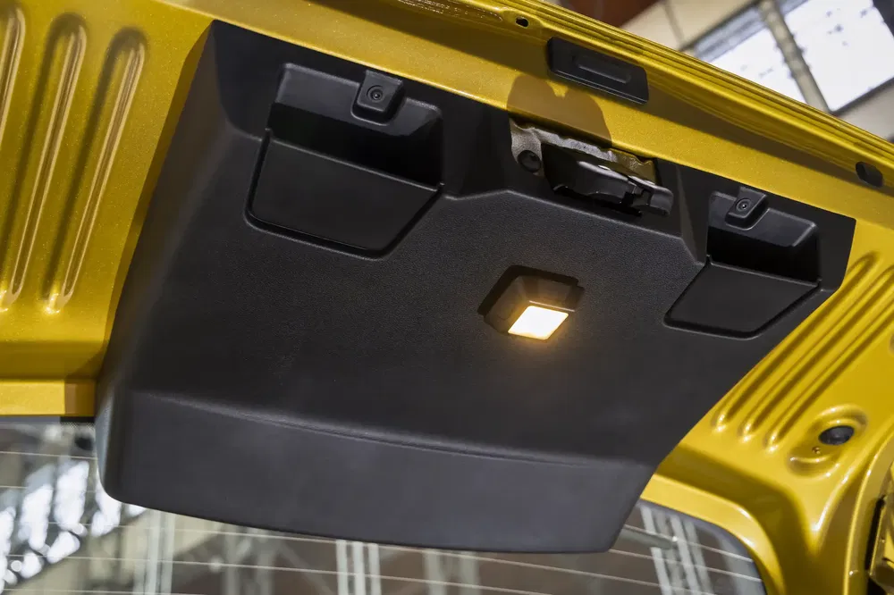 Geopende achterklep van een gele Suzuki Jimny Sierra met interieurverlichting aan.