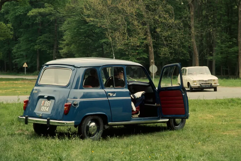 Blauwe Renault 4L met open deuren in een bosrijke omgeving.