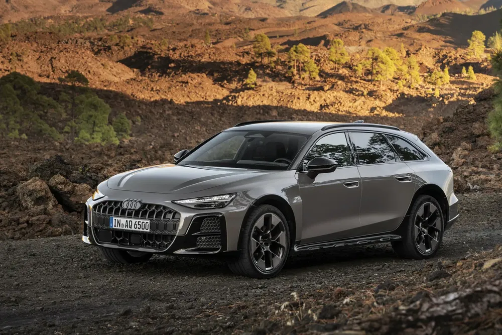 Grijze Audi A6 Allroad tegen een rotsachtig, dor landschap.