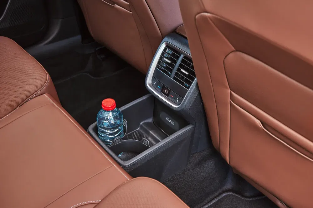 Intérieur Audi Q10, siège arrière avec porte-gobelet et bouteille d'eau, cuir marron élégant.